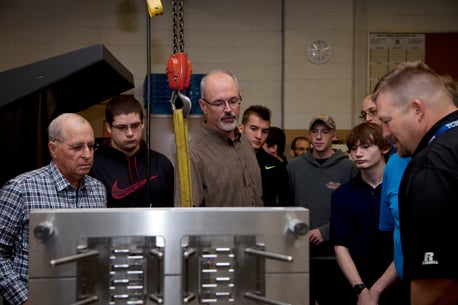 Rodon employee shows a group of students a plastic injection mold