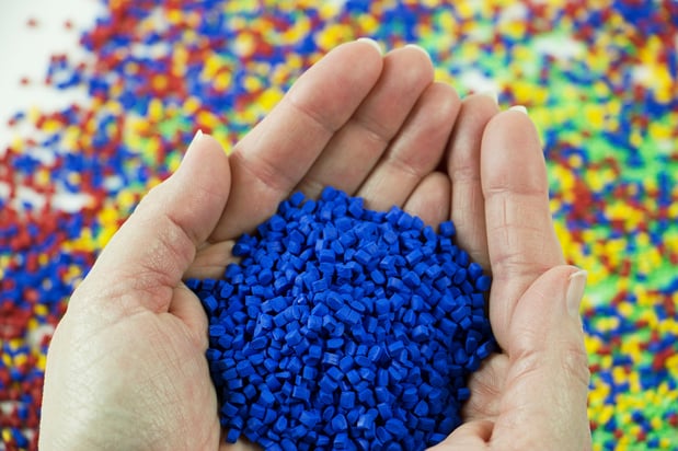 blue plastic injection molding colorant in a person's hands